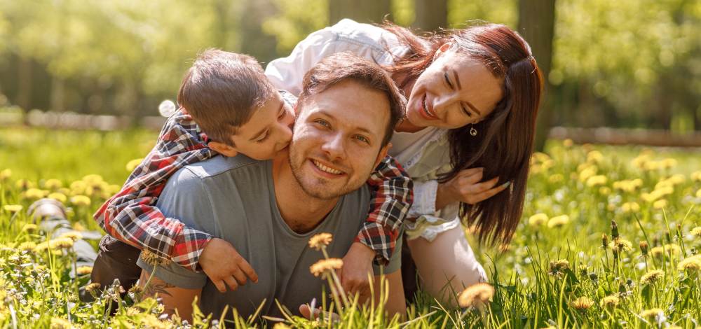 A happy business owning dad and mom play with their sone in a field